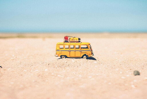 Gelber Mini-Modell-Camping-Van auf dem Sand