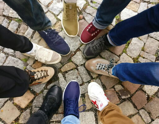 Personen bilden mit ihren bunten Schuhen einen kleinen Kreis.