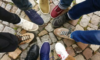 Personen bilden mit ihren bunten Schuhen einen kleinen Kreis.