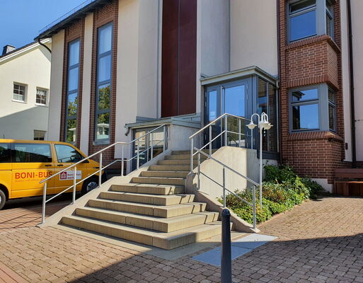 Der gelbe "Boni"-Bus steht vor den Außenwänden des Pfarrhauses, hinter denen sich das Pfarrbüro verbirgt.