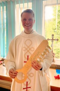 Pfarrer Theuermann in der Sakristei mit symbolischen Pappschlüssel in der Hand